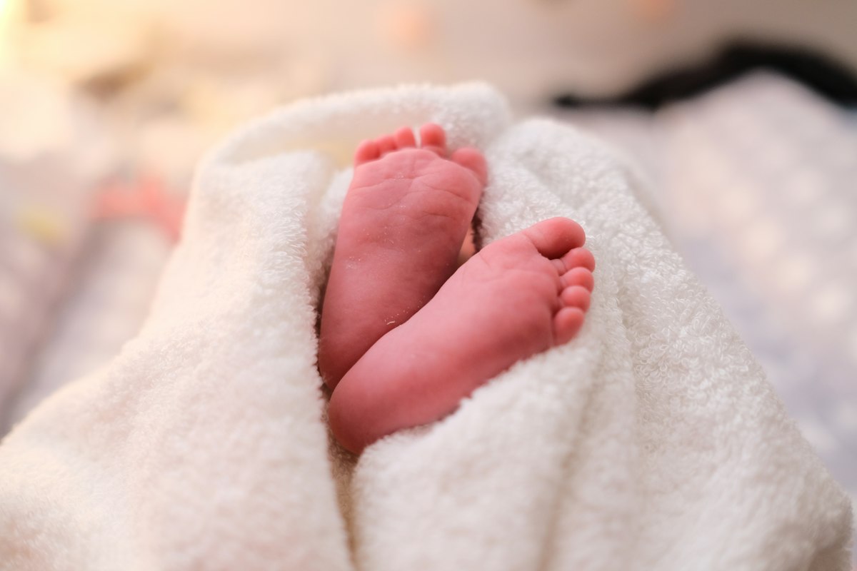 Kleine Babyfüße schauen unter einer weichen weißen Decke hervor