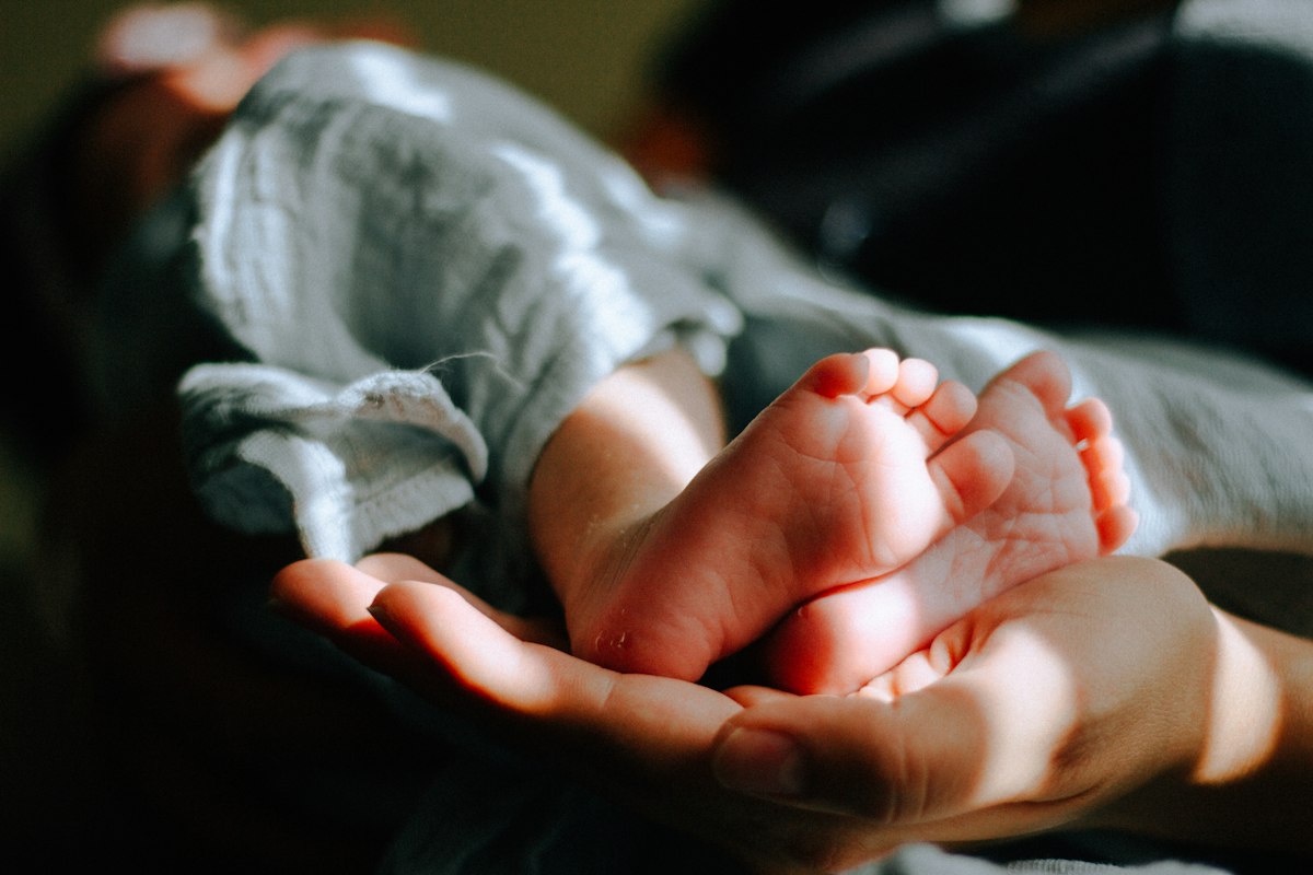 Eine Mutter hält die kleinen Füße ihres Babys in den Händen