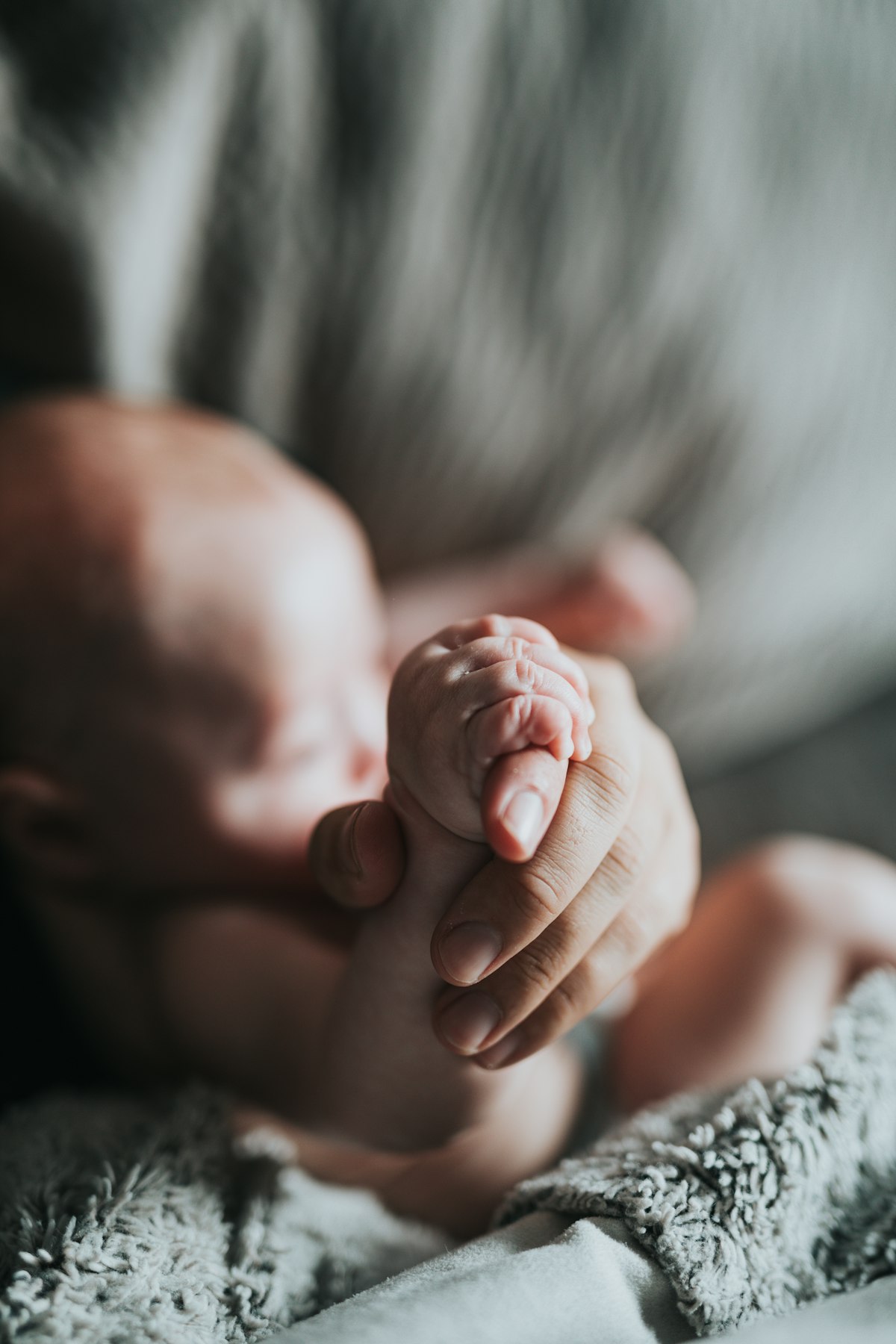 Eine erwachsene Hand hält die winzige Hand eines Neugeborenen