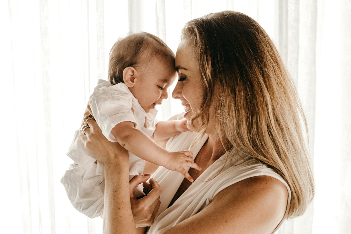 Eine lächelnde Mutter hält ihr Baby liebevoll in den Armen und berührt es mit der Stirn