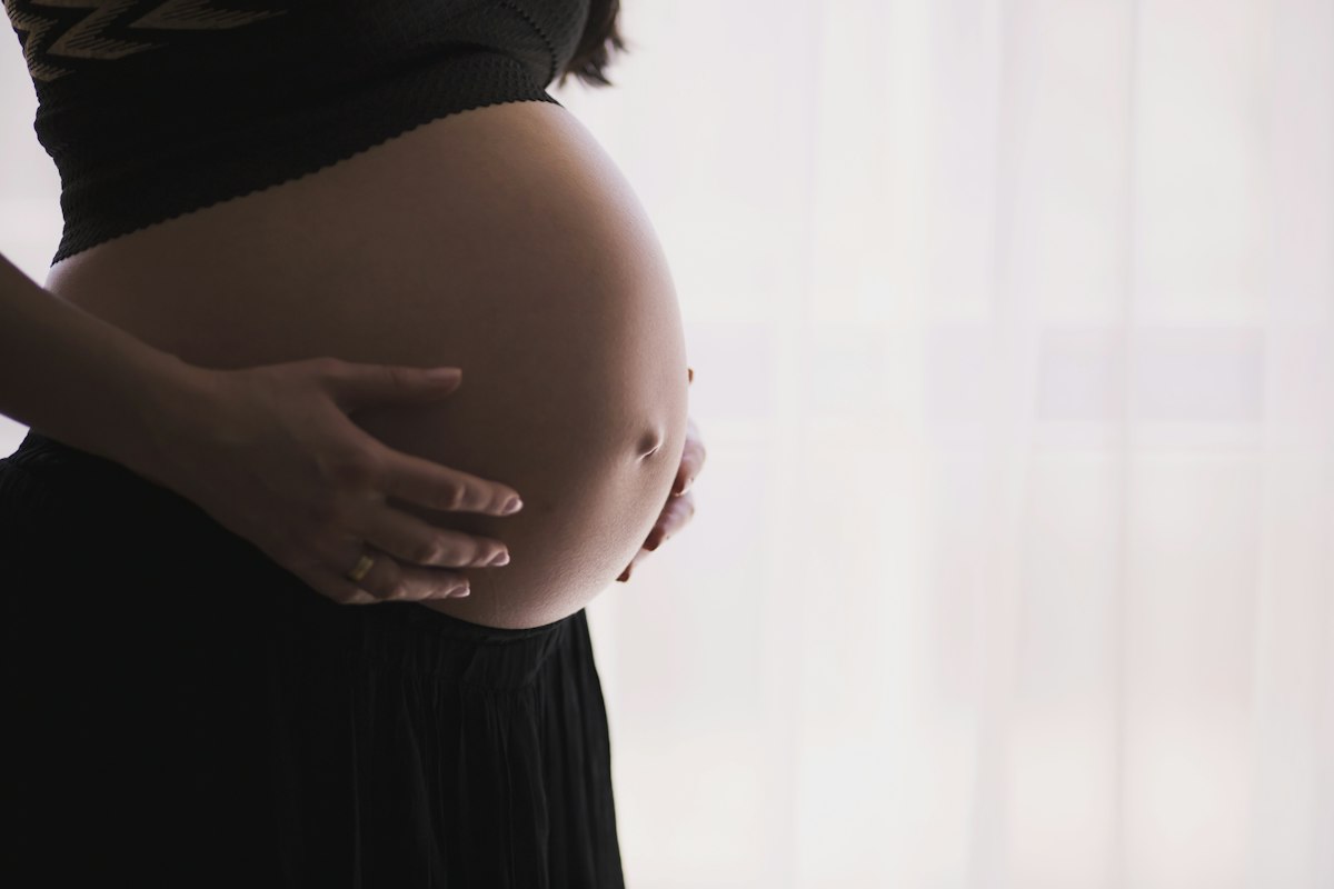 Eine schwangere Frau hält liebevoll ihren Babybauch